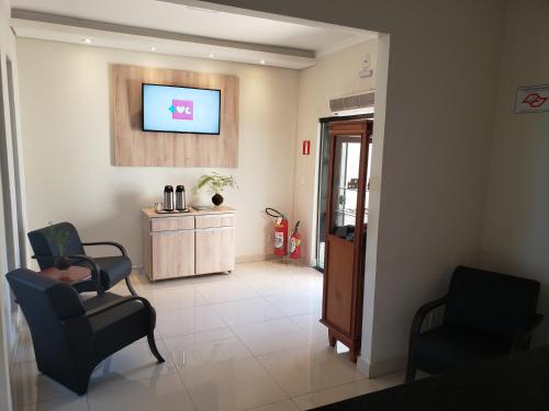 a waiting room with two chairs and a tv on the wall at Proença Hotel in Barretos