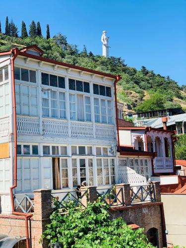 a large white building with a hill in the background at Betlemi Old Town Hotel in Tbilisi City