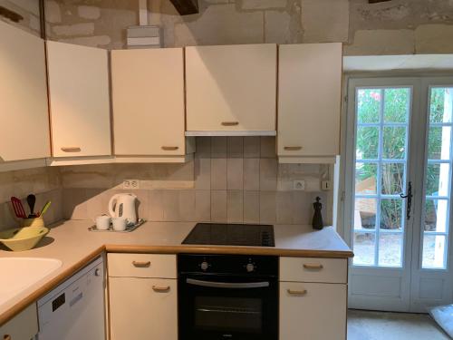 une cuisine avec des armoires blanches et un four à plaques de cuisson dans l'établissement Gite de la Tour des Abbés, à Fontvieille