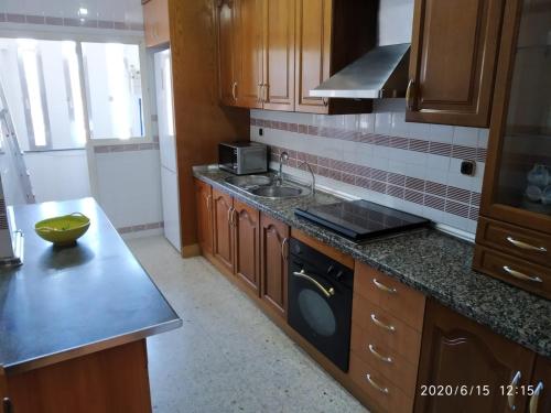 kuchnia z drewnianymi szafkami, zlewem i zmywarką do naczyń w obiekcie La Conchita w mieście Almería