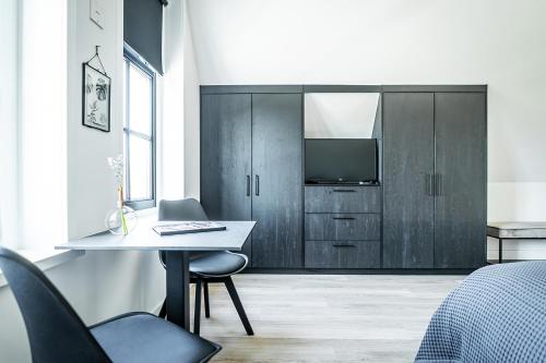 a bedroom with a desk and a tv in a room at Het Vergulde Visje in Den Burg