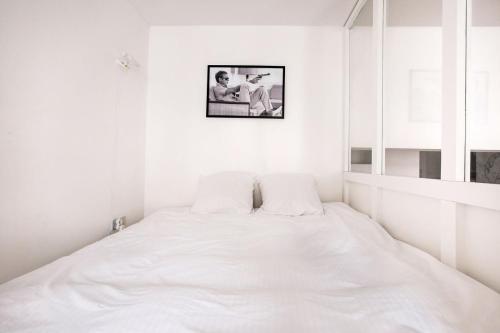 - un lit blanc dans une chambre blanche avec une photo sur le mur dans l'établissement LA CABANE Lille Centre, à Lille