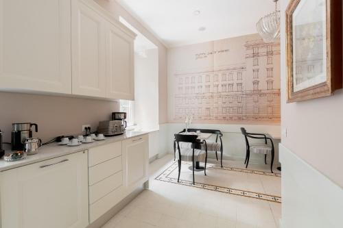 a kitchen with white cabinets and a table with chairs at Queen Meg Roma in Rome