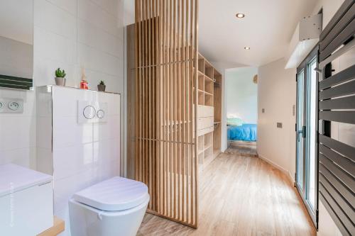 een badkamer met toilet en houten wand bij THE COSY in Arcueil