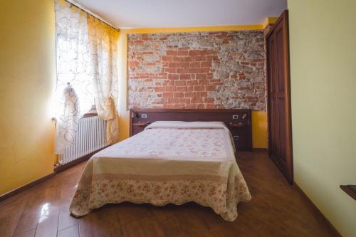 a bedroom with a bed and a brick wall at All'Ombra del Castello in Cigliè