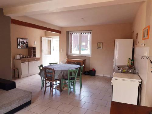 a kitchen and dining room with a table and a refrigerator at Gîte cosy 4 à 9 personnes in Buffières