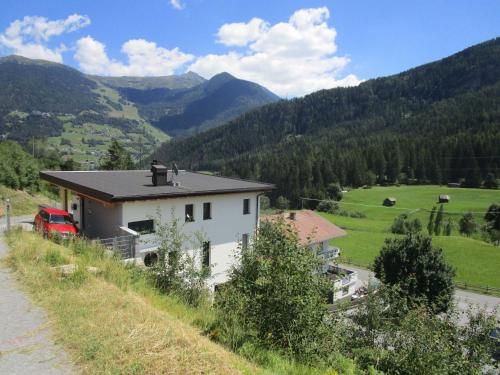 a house on a hill with mountains in the background at Apartment Skyline in Wenns