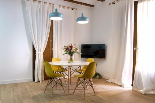 ein Esszimmer mit einem Tisch und gelben Stühlen in der Unterkunft LA MOMA Apartments & Room in Xàtiva