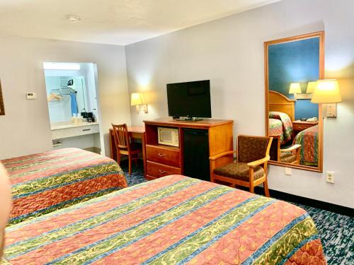 a hotel room with two beds and a flat screen tv at Scottish Inns Westcott Street in Houston