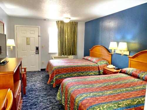 a hotel room with two beds and a television at Scottish Inns Westcott Street in Houston
