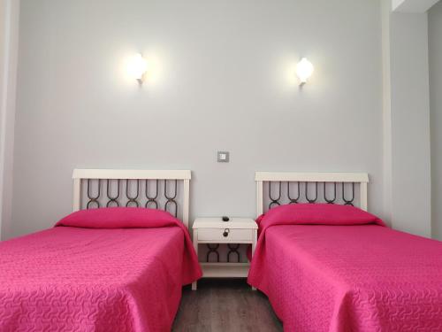 two beds in a room with pink sheets at Pensión Dorada in Noja