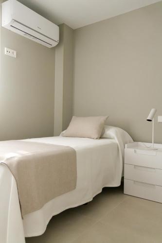 a white bedroom with a bed and a night stand at Sosiego Home in Puerto de Mazarrón