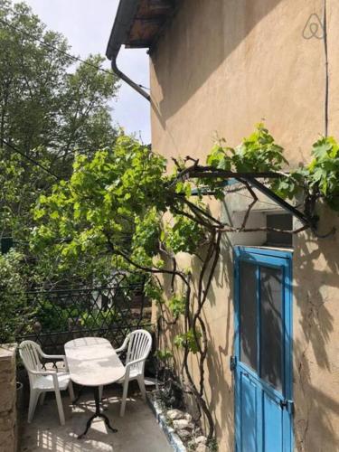 une table et des chaises à côté d'un bâtiment avec une porte bleue dans l'établissement Charmante maison de village à Fontaine-de-Vaucluse, à Fontaine-de-Vaucluse
