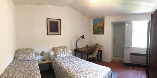 - une chambre avec 2 lits, un bureau et une fenêtre dans l'établissement Charmante maison de village à Fontaine-de-Vaucluse, à Fontaine-de-Vaucluse