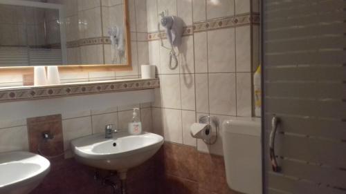 a bathroom with a sink and a toilet and a phone at Napsugár Vendégház in Kiskőrös