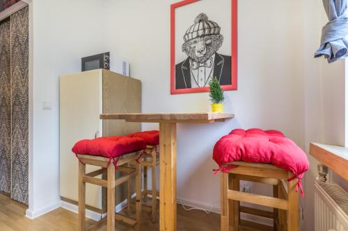 kuchnia ze stołem i 2 stołkami z czerwonymi poduszkami w obiekcie Apartament Biały Miś Centrum w Zakopanem