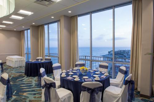 a conference room with tables and chairs and large windows at Crowne Plaza Hotel Ventura Beach, an IHG Hotel in Ventura