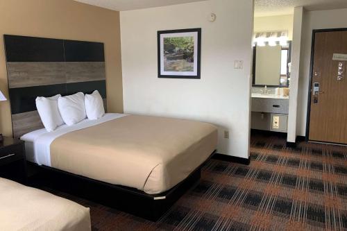 a hotel room with a large bed and a bathroom at Baymont by Wyndham Waupun in Waupun