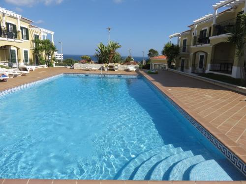 una gran piscina azul junto a algunos edificios en Encantador T1 praia Senhora da Rocha - Algarve en Porches