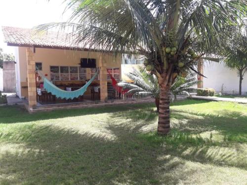 a palm tree in front of a building with hammocks at Pousada Nosso Recanto Camocim in Camocim