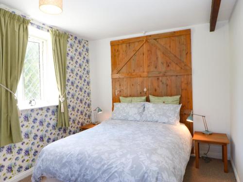 a bedroom with a bed with a wooden headboard at Bilberry Nook Cottage in Westgate