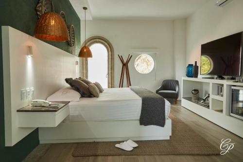 a bedroom with a white bed and a tv at Hotel Boutique de Cantera Y Plata in Taxco de Alarcón