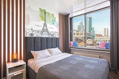 a bedroom with a bed and a window with the eiffel tower at Apartments Home Hotel in Yekaterinburg