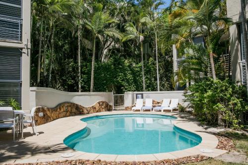 a swimming pool in a yard with chairs and trees at Noosa Blue Resort in Noosa Heads