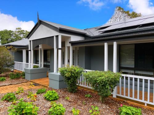 a house with a white fence and some plants at Koala Cabins Sunshine Coast in Mapleton