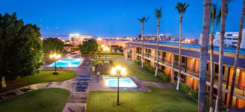 a building with two swimming pools and palm trees at night at Hotel Colonial Mexicali in Mexicali