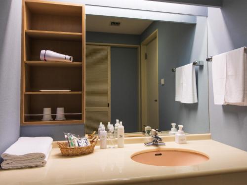 baño con lavabo y espejo grande en Okinawa Grand Mer Resort, en Okinawa City