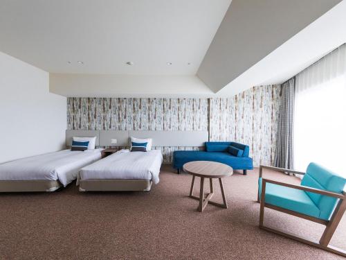 Habitación de hotel con 2 camas y sofá azul en Okinawa Grand Mer Resort en Okinawa City