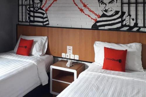 two beds with red pillows in a room at RedDoorz Plus @ Doorman Guest House in Bandung