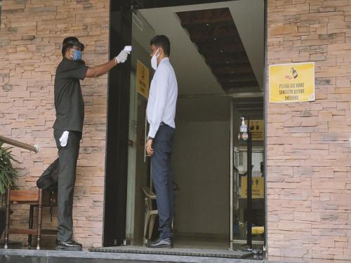 two men wearing masks standing outside of a building at Heritage Inn in Mysore