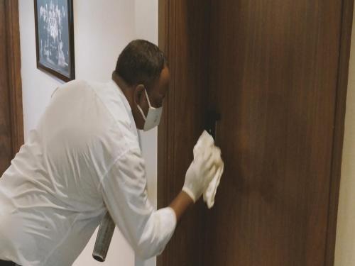 a man is cleaning a door with a towel at Heritage Inn in Mysore
