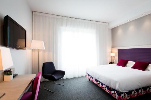 a hotel room with a bed and a desk and a tv at Best Western Plus Hotel Plaisance in Villefranche-sur-Saône