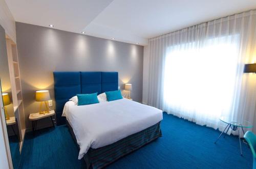 a bedroom with a large bed and a large window at Best Western Plus Hotel Plaisance in Villefranche-sur-Saône