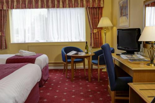 Tiverton Hotel Lounge & Venue formally Best Western في تيفرتون: غرفة بالفندق بها مكتب وسرير وتلفزيون