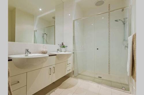 La salle de bains est pourvue de 2 lavabos et d'une douche en verre. dans l'établissement Top-floor beachside apartment with views, à Casuarina