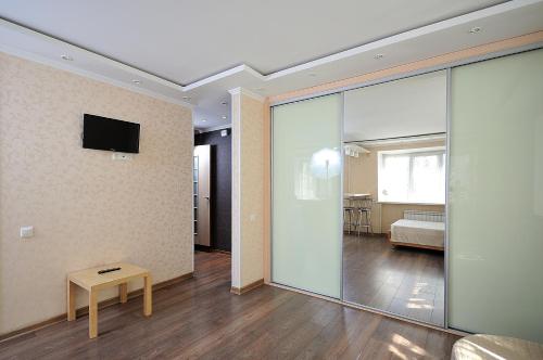 オムスクにあるOmsk Sutki Apartment on Zhukovaのリビングルーム(テーブル、壁掛けテレビ付)
