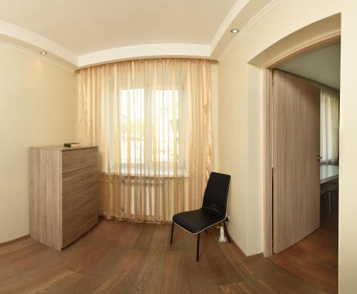 オムスクにあるOmsk Sutki Apartments Krasny Put 67の椅子、ドレッサー、窓が備わる客室です。