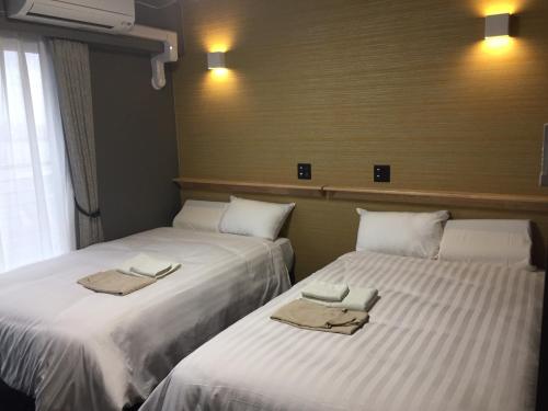 two beds sitting next to each other in a room at Omura Station Hotel Nagasaki Airport in Omura