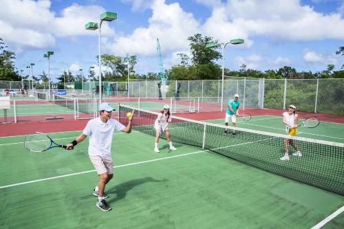 a group of people playing tennis on a tennis court at Pacific Islands Club Saipan in Chalan Kanoa