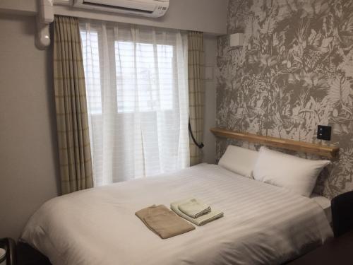 a bedroom with a bed with two towels on it at Omura Station Hotel Nagasaki Airport in Omura