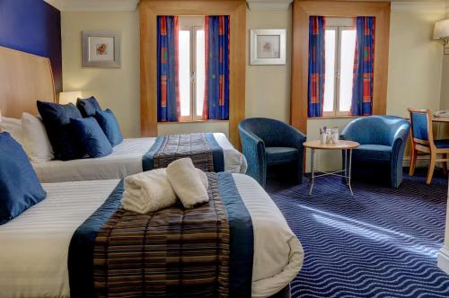 a hotel room with two beds and a table and chairs at The Bull Hotel; Sure Hotel Collection by Best Western in Peterborough