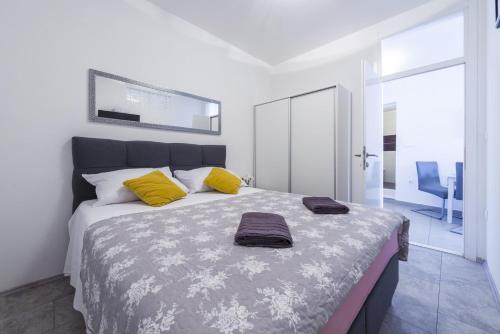 a white bedroom with a large bed with yellow pillows at Tinker Bell Apartment in Dubrovnik
