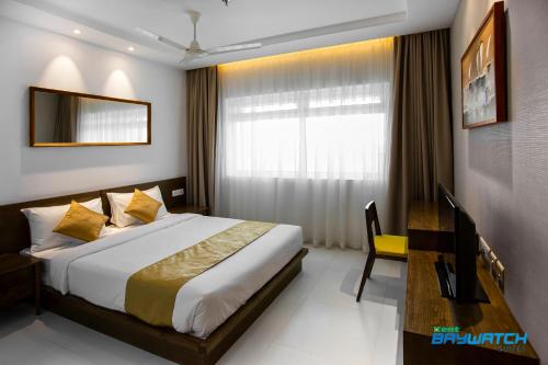 a bedroom with a bed and a desk and a window at Kent Baywatch Suites in Cochin