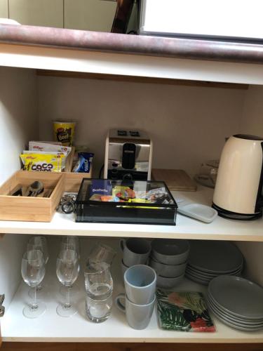 a shelf with plates and glasses and a coffee maker at Sea Change Guesthouse in Apollo Bay