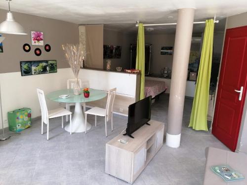 a living room with a table and a tv at Un petit coin de paradis in Taradeau