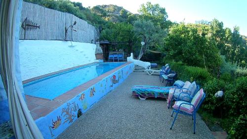 a swimming pool with chairs and a couch next to it at Alojamiento Rural El Brazal in Lanjarón